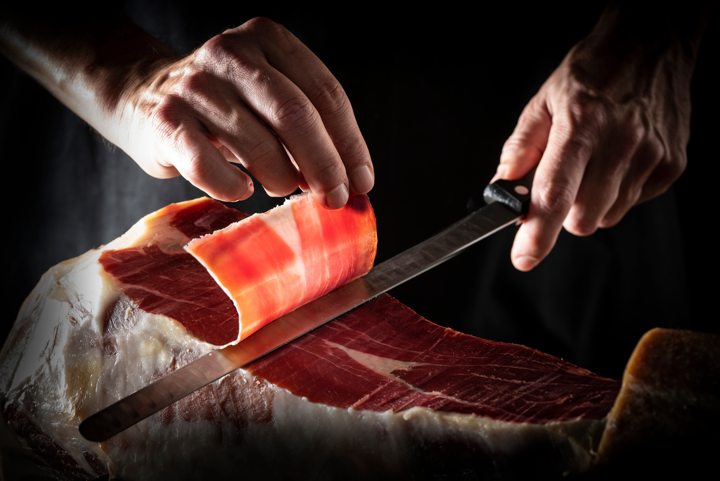 Iberian ham serrano ham slice cutting hands and knife